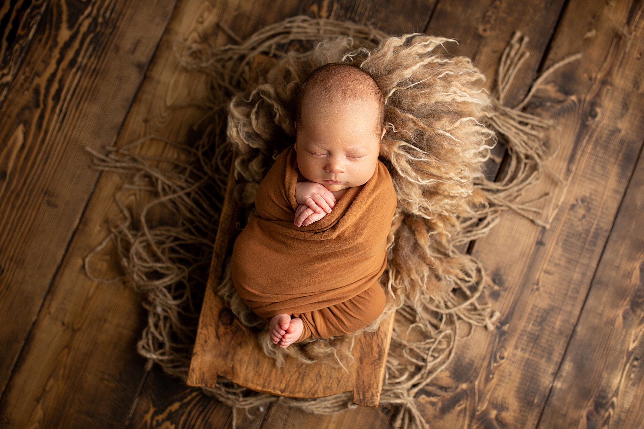 Baby boy rustic dark wood newborn photography, wrapped in prop.