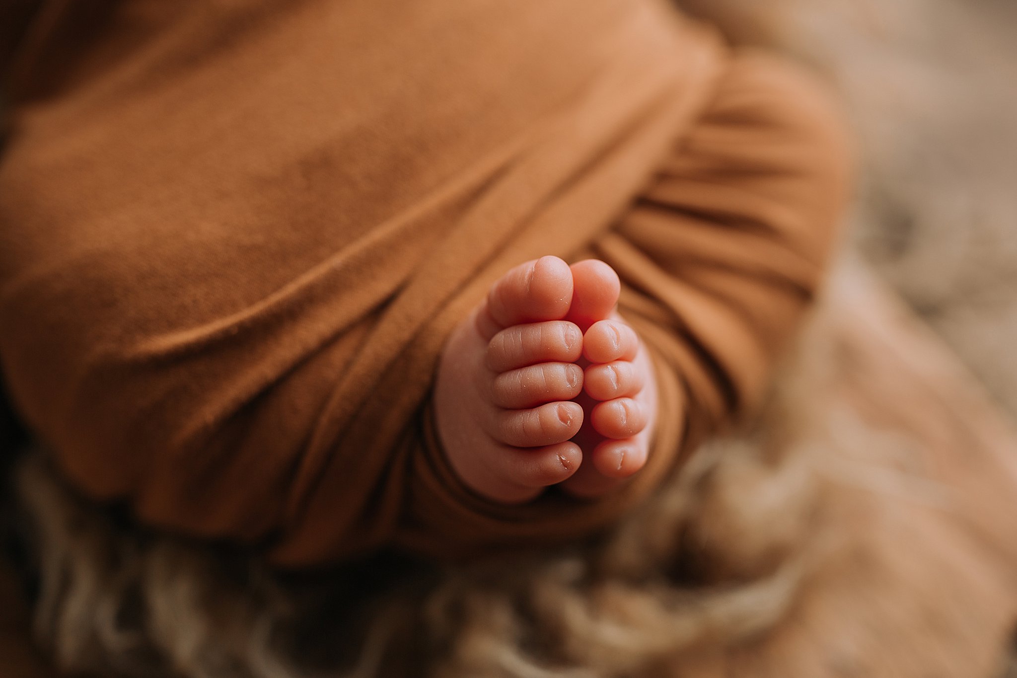 Baby boy newborn photography warm caramel tones, macro photography of toes.