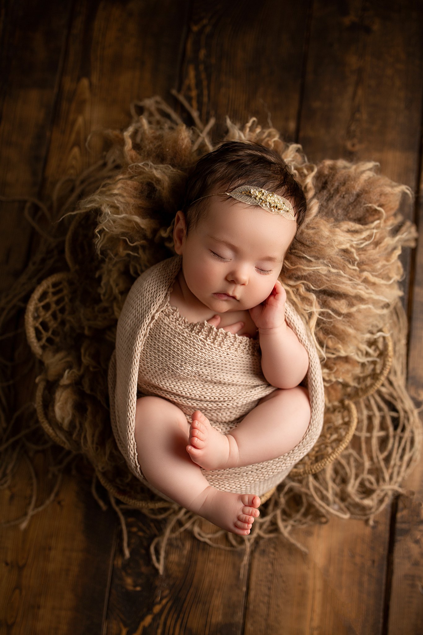 Baby girl newborn photography neutral set with fur on dark wood backdrop