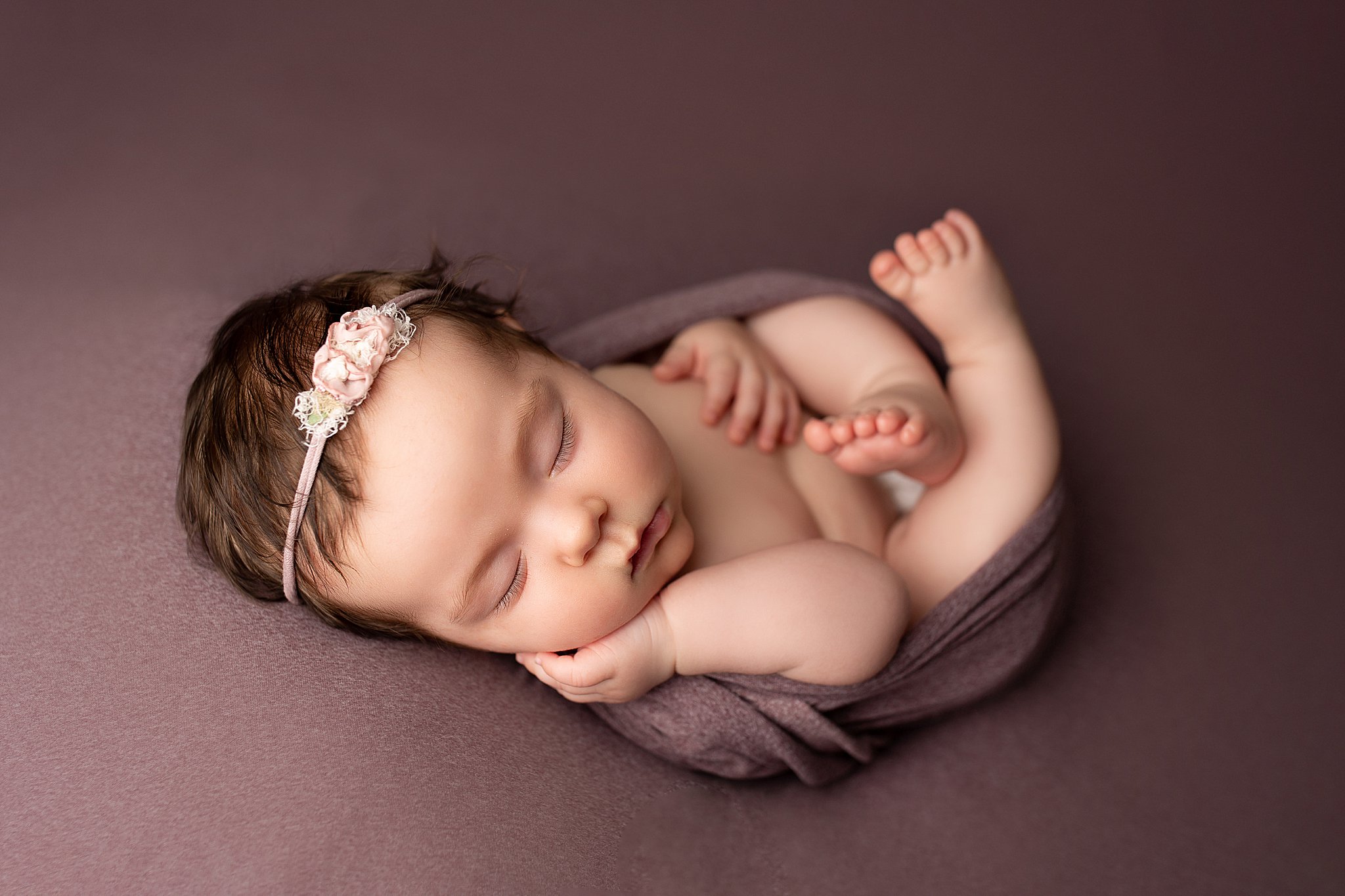Baby girl newborn photography egg wrap on purple backdrop